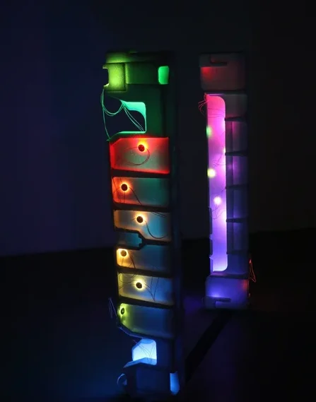 Two illuminated, abstract sculptures with vibrant colours against a dark background.